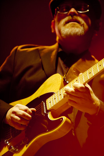 Gros plan sur les mains du musicien tout en gardant en second plan la concentration sur son visage.